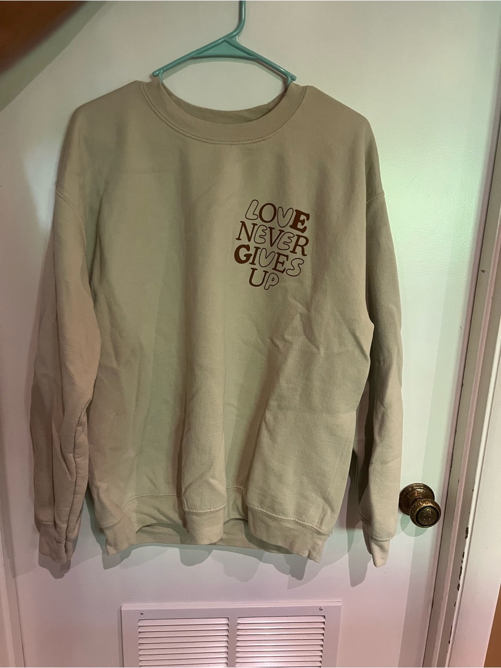 Gildan Crewneck Sweatshirt in Light Beige with 'Love Never Gives Up' Print